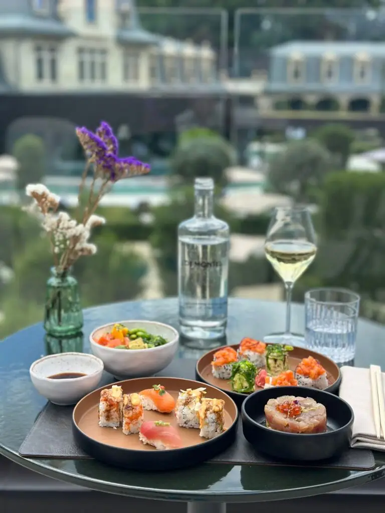 Elegante cena all'aperto con sushi, una bottiglia d'acqua e un bicchiere di vino bianco.