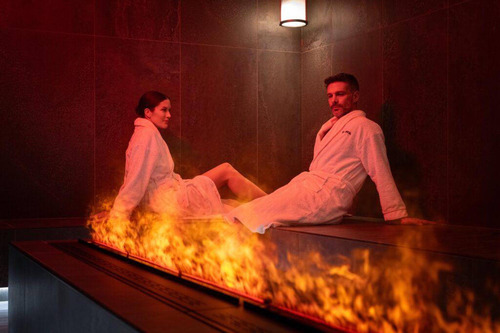 Una coppia si rilassa in una spa De Montel, ammirando il fuoco.