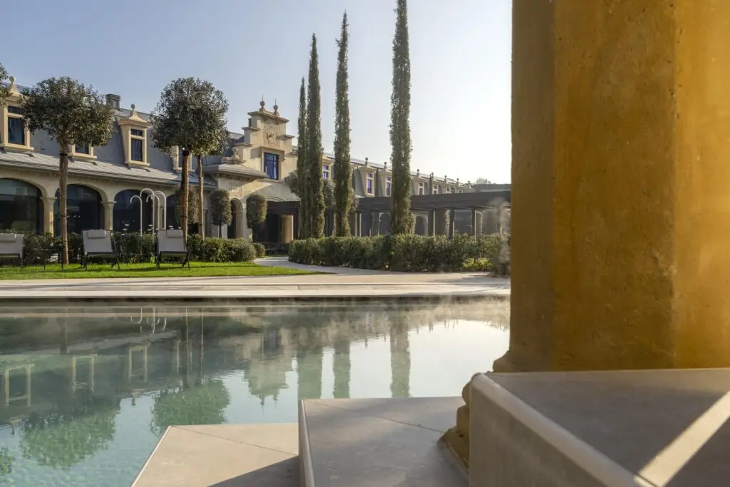Tranquilla piscina all'aperto di una spa di lusso, che riflette uno splendido edificio. Perfetta per cerimonie di benessere.