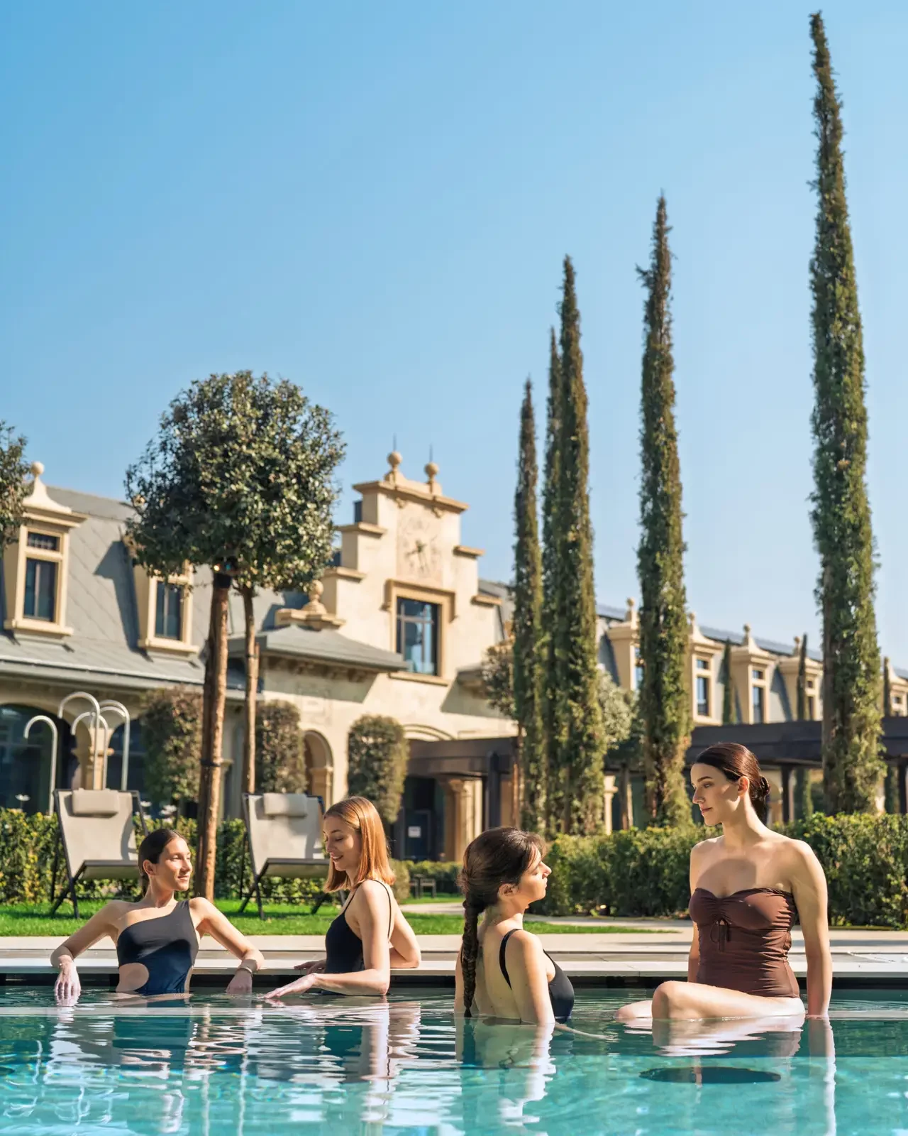 Quattro donne che si rilassano in piscina con una villa sullo sfondo