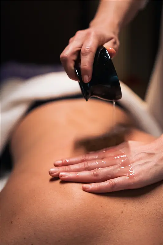 Massaggio Gua Sha sulla schiena con olio. Benessere.