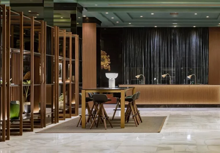 Lobby di hotel moderno con bancone reception illuminato e tavoli alti