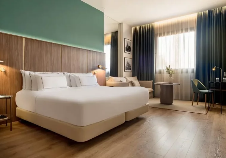 Camera da letto moderna con letto king-size, testiera in legno e pareti color ottanio.