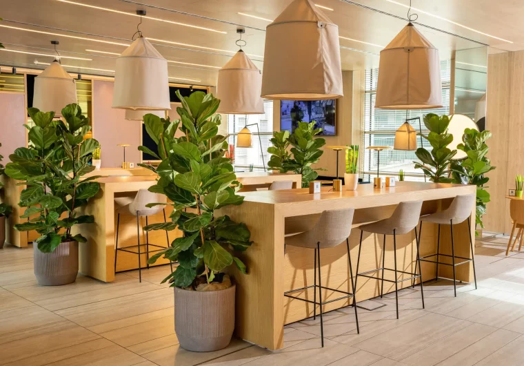 Lussuoso spazio lounge con piante da interno e tavoli in legno per lavorare.
