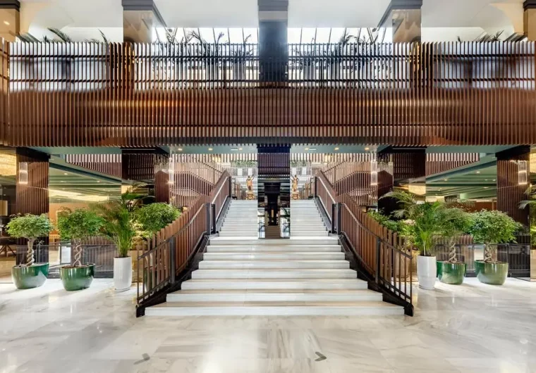 Atrio di hotel con scale bianche, piante verdi e design moderno