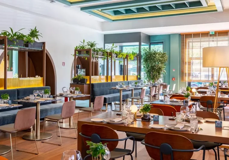 Interno moderno di un ristorante con tavoli apparecchiati e piante verdi